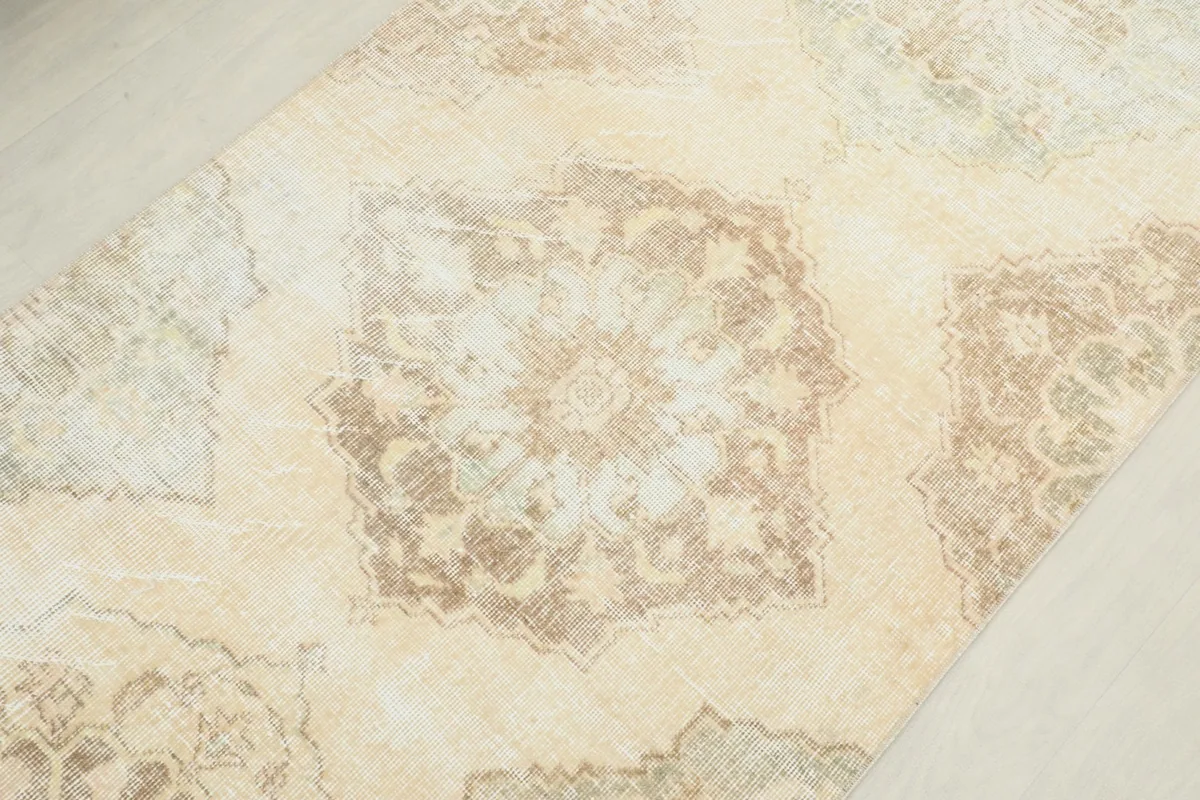 Detailed view of a central geometric medallion on the ivory runner rug with tan and olive tones.