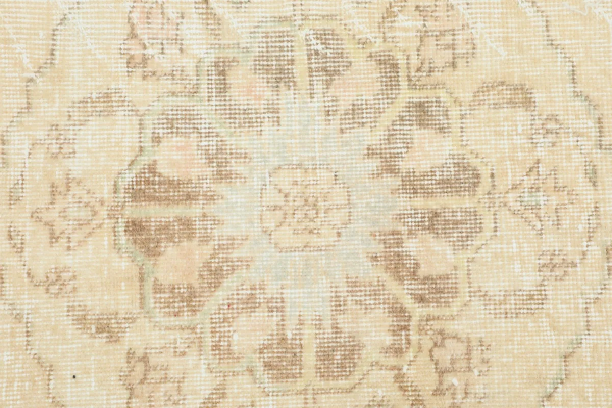 Macro view of the low wool pile and faded colors of a geometric medallion on the runner.
