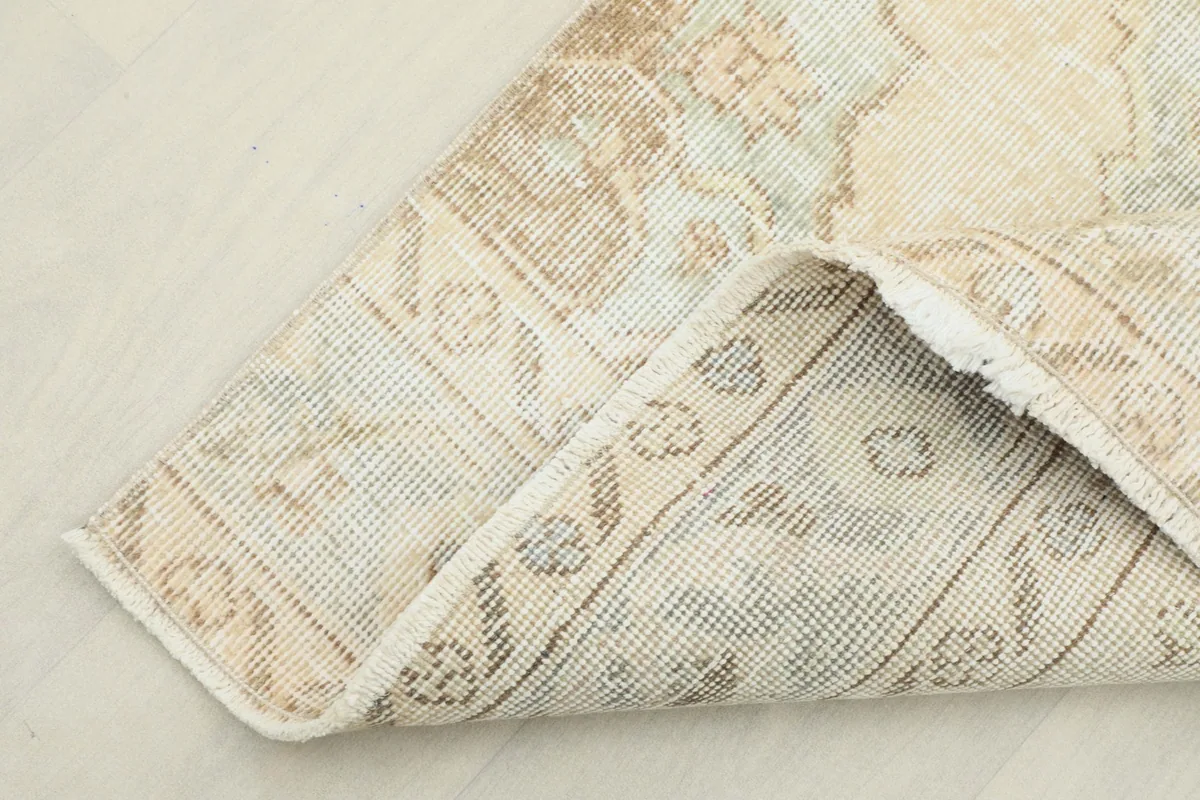 Corner of the runner rug folded to show the hand-knotted cotton foundation and reverse side.