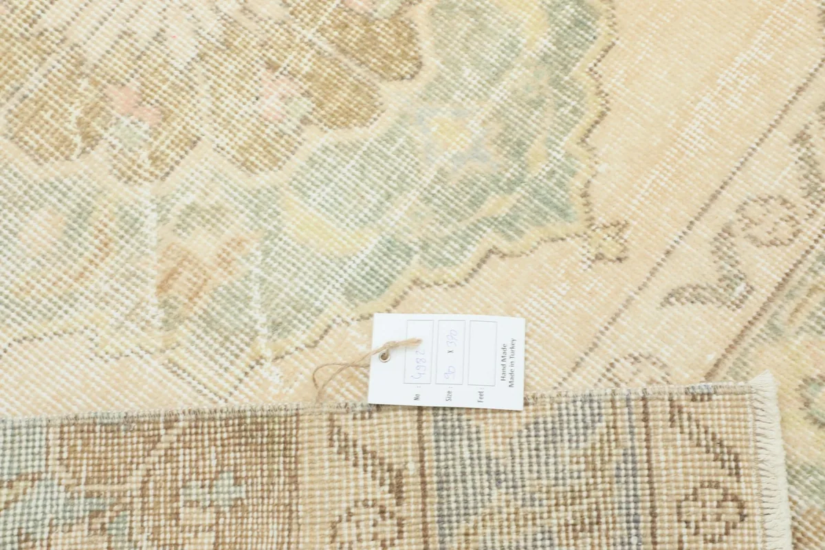 Detail of the rug's surface with a product tag, showing the weave and muted colors.