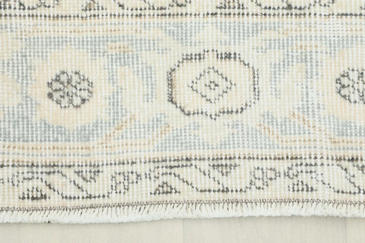 Close-up of the rug's end, showing the border details and subtle blue and ivory tones.