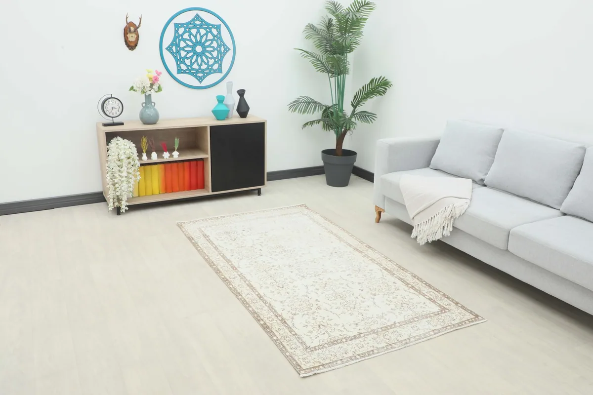 Ivory and tan floral rug placed in a modern living room setting with a gray sofa
