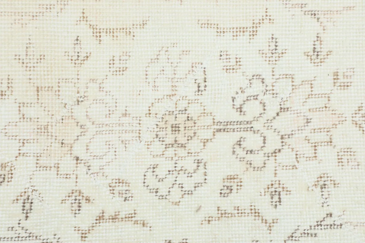 Detailed close-up of the hand-knotted wool pile showing ivory and tan floral design