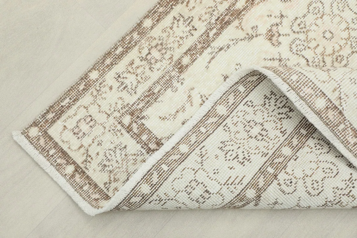 Corner of the rug folded back to show the cotton foundation and hand-knotted construction