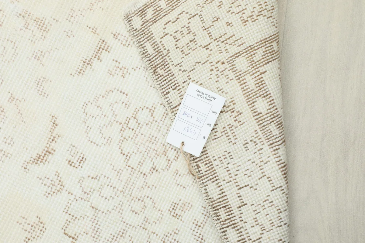 Reverse side of the rug with a care label, showing the tight knotting on the cotton foundation