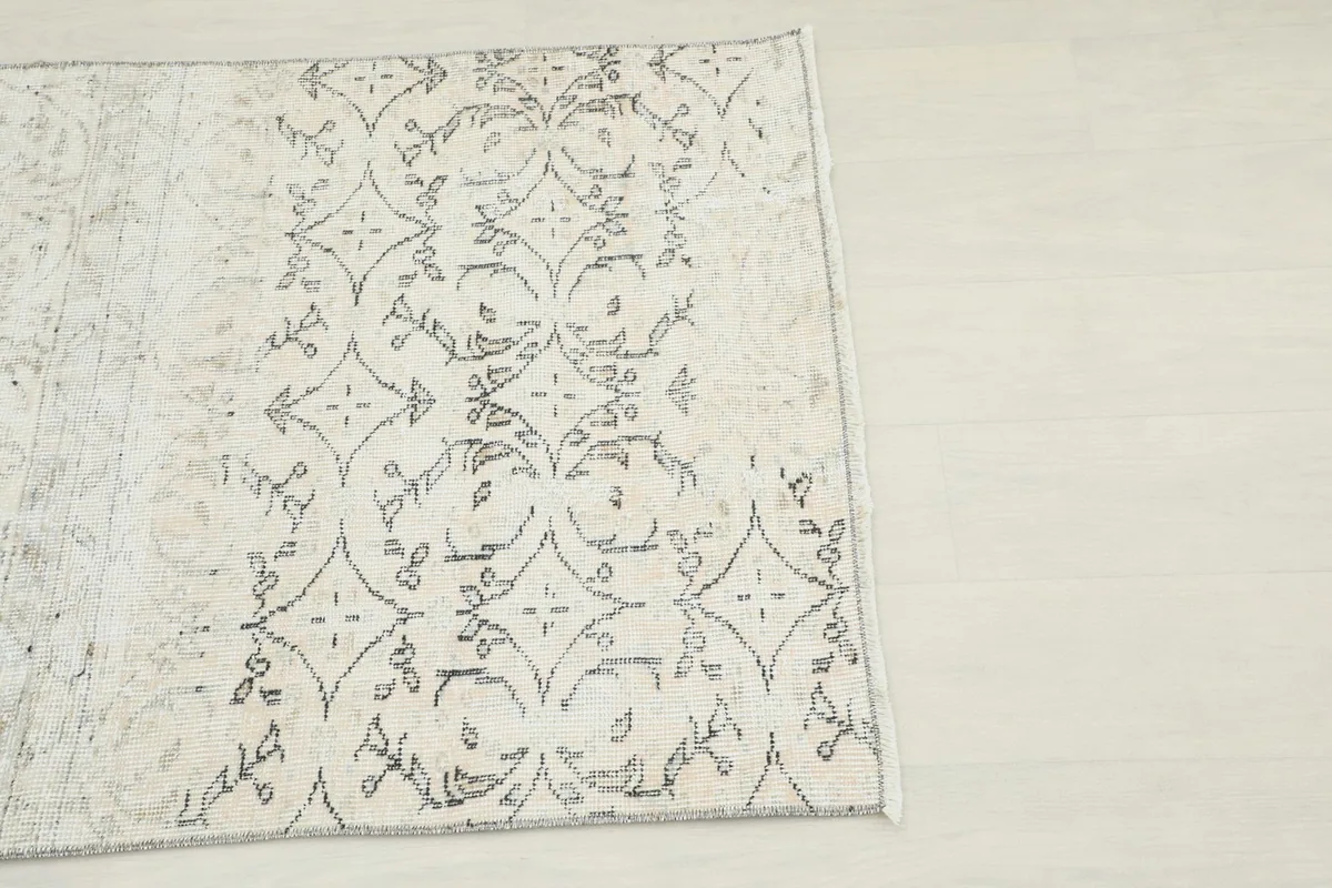 Close-up of the geometric charcoal pattern on the ivory field of the vintage Anatolian rug.