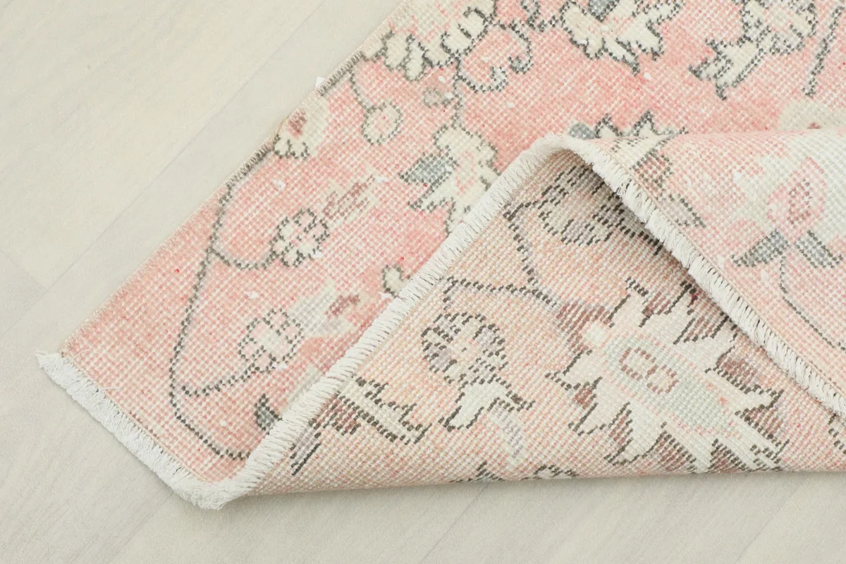 Corner of the rug folded to show the cotton foundation and reverse side of the hand-knotting.