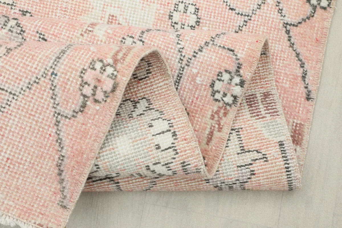 Close-up of the folded rug, highlighting the density of the knots and the vintage wear.
