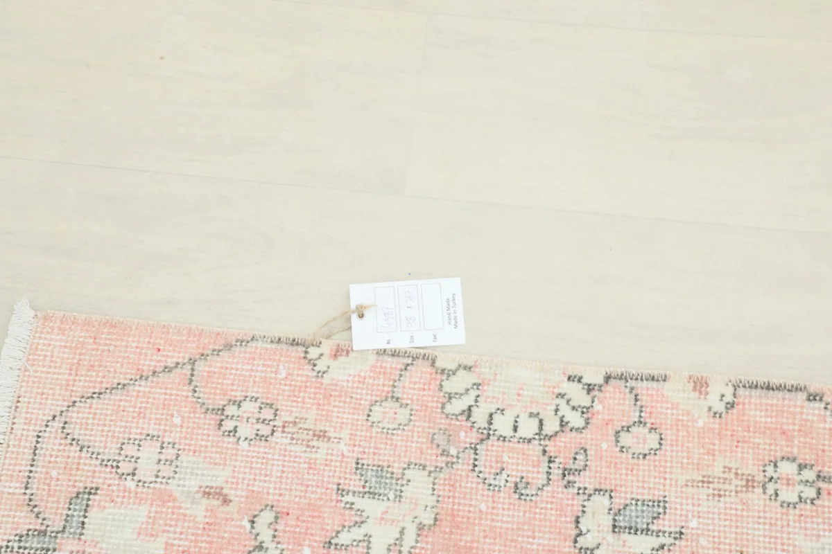 Rug corner with a label, showing the hand-knotted craftsmanship and wool material.