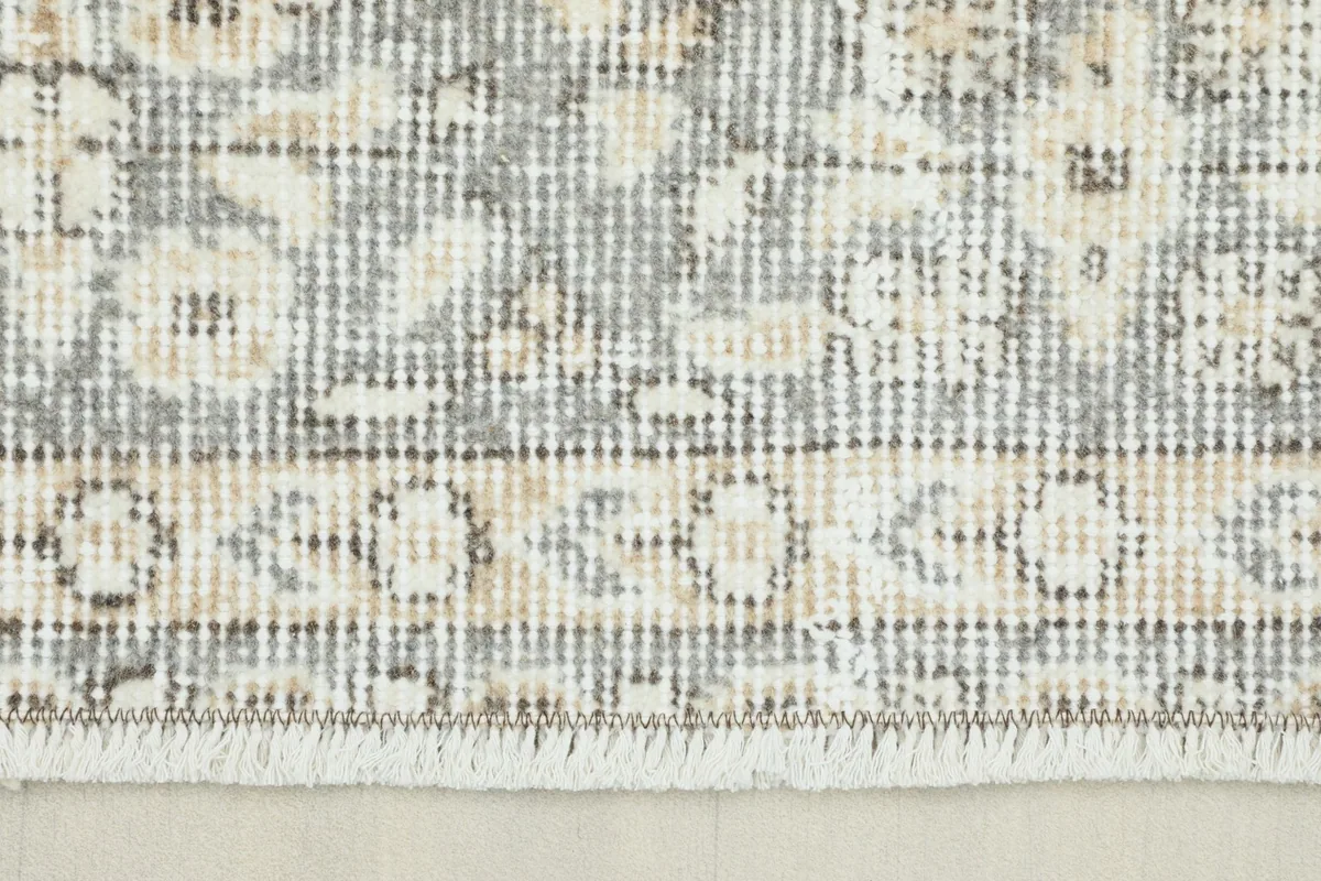 Close-up view of the gray and tan border pattern and fringe detail on the rug