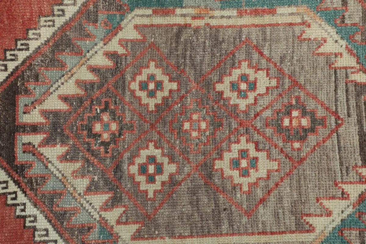 Detailed view of the diamond motifs within the medallion, showing the blend of rust, gray, and blue.