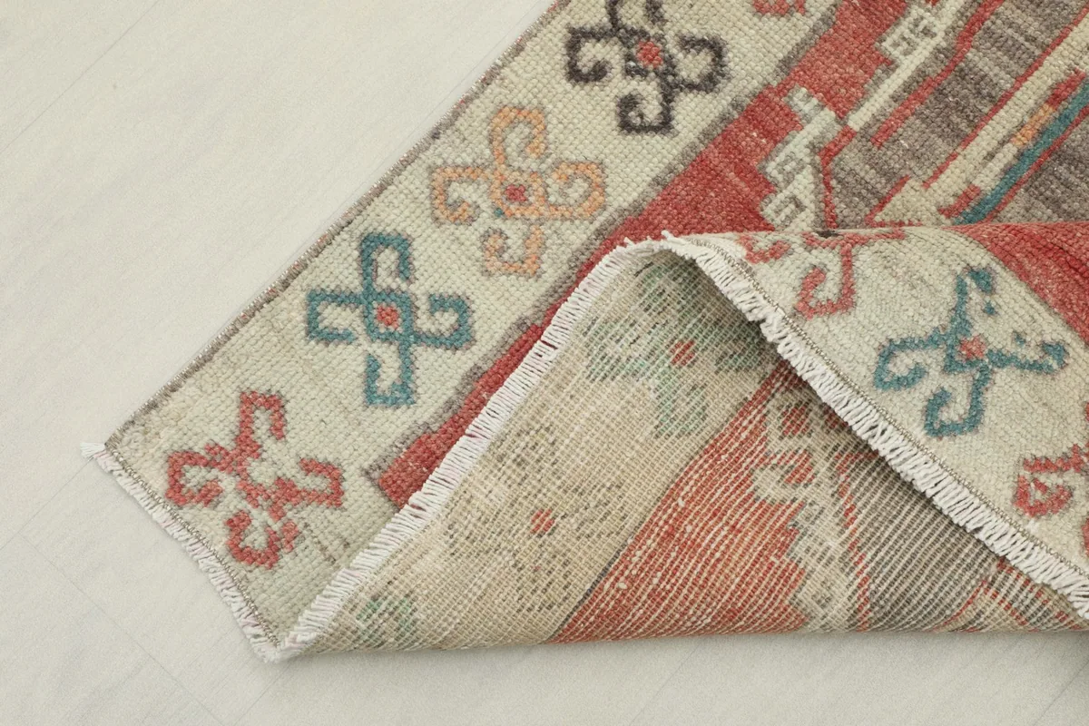View of the rug's corner folded to show the hand-knotted wool pile and cotton foundation.