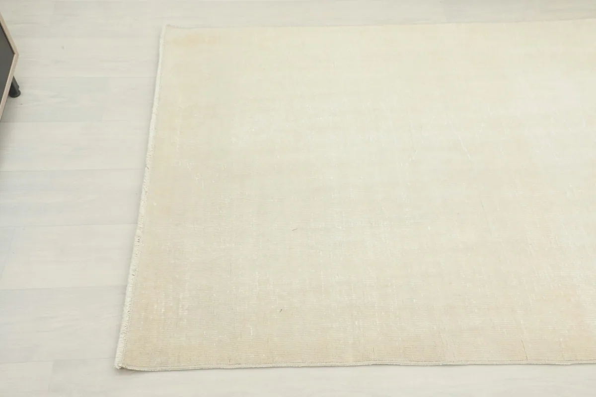 Corner view of the ivory area rug on a light floor, showing the edge and a hint of the room.