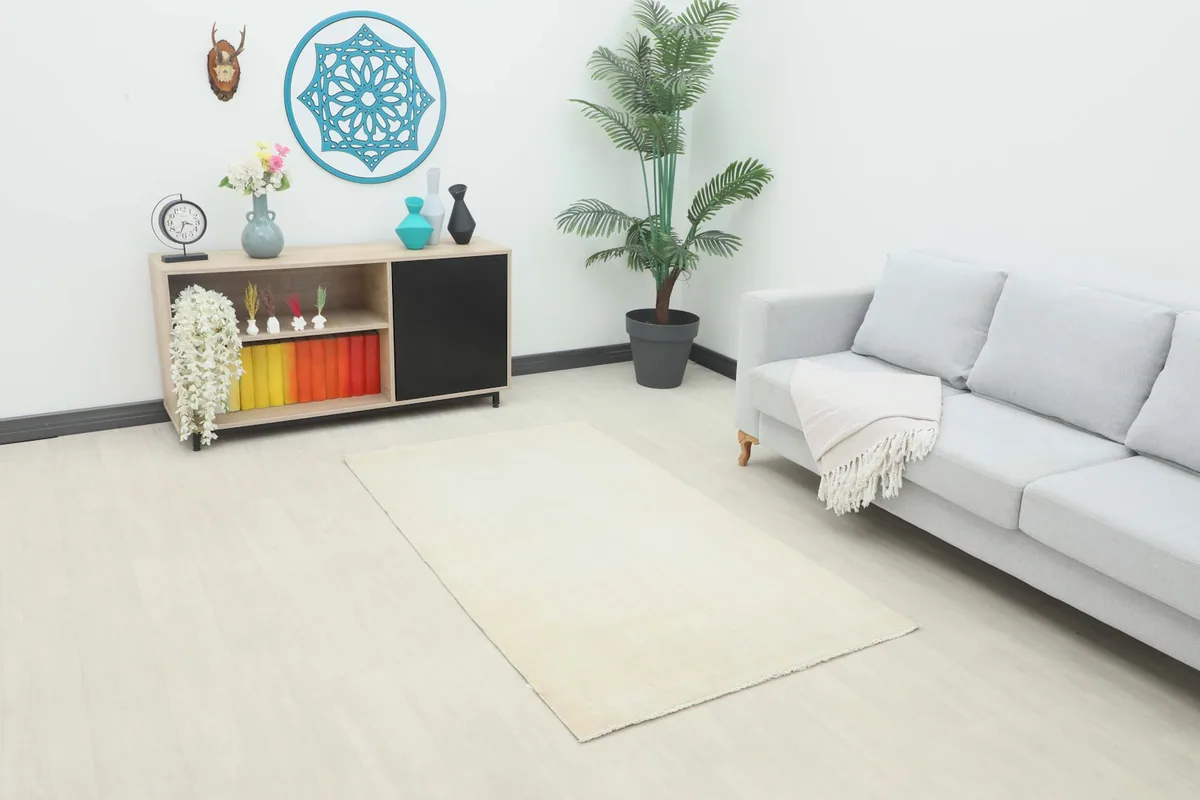 Ivory vintage wool rug placed in a modern living room setting with a gray sofa and light wood flooring.