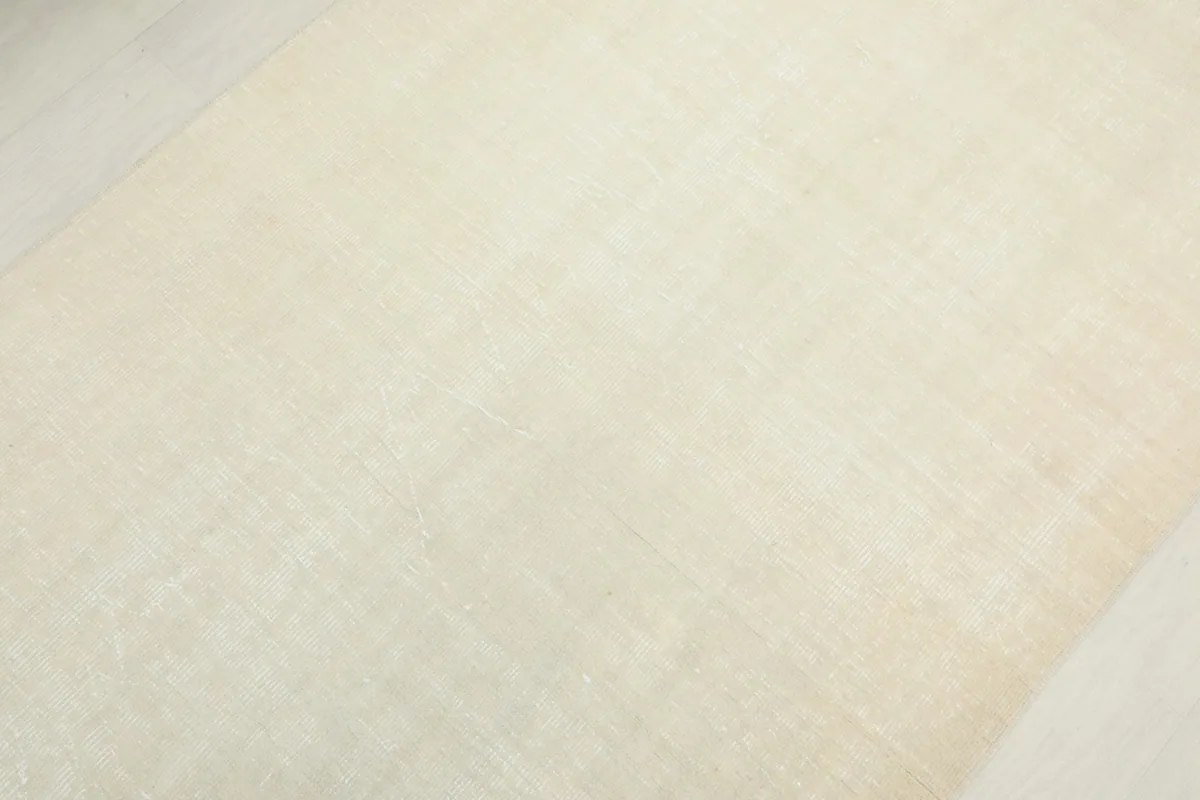 Detailed view of the rug's surface, revealing the low pile and subtle color shifts in the ivory wool.
