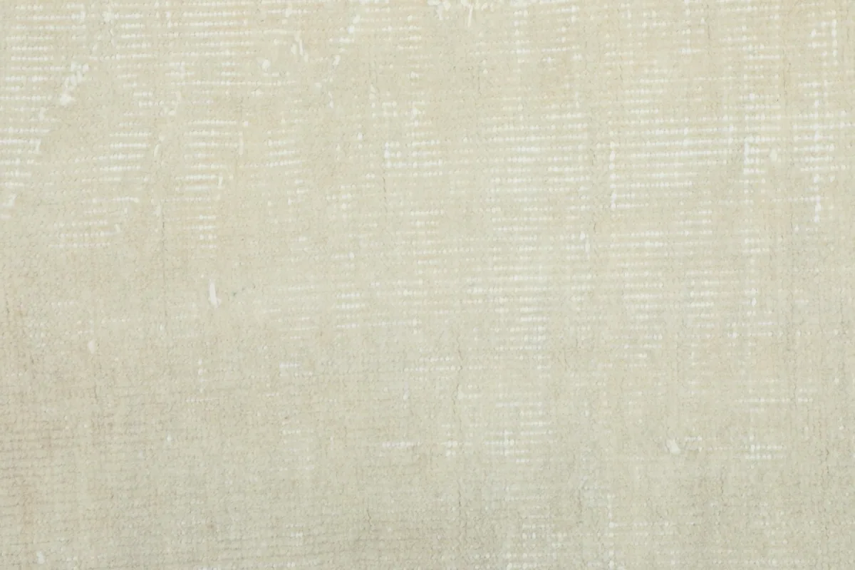 Close-up of the low wool pile, showing the hand-knotted texture and soft, muted ivory tones.