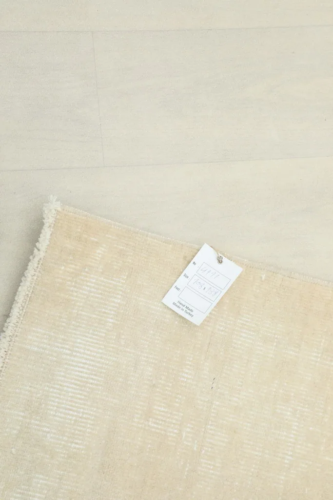 View of the rug's backing with a product tag attached, indicating its origin and material.
