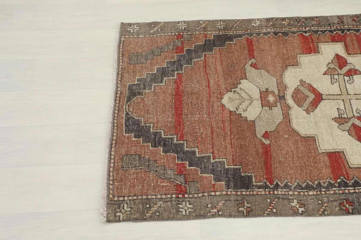 Angled detail of the rug's side, showing the transition from the rust field to the gray border.