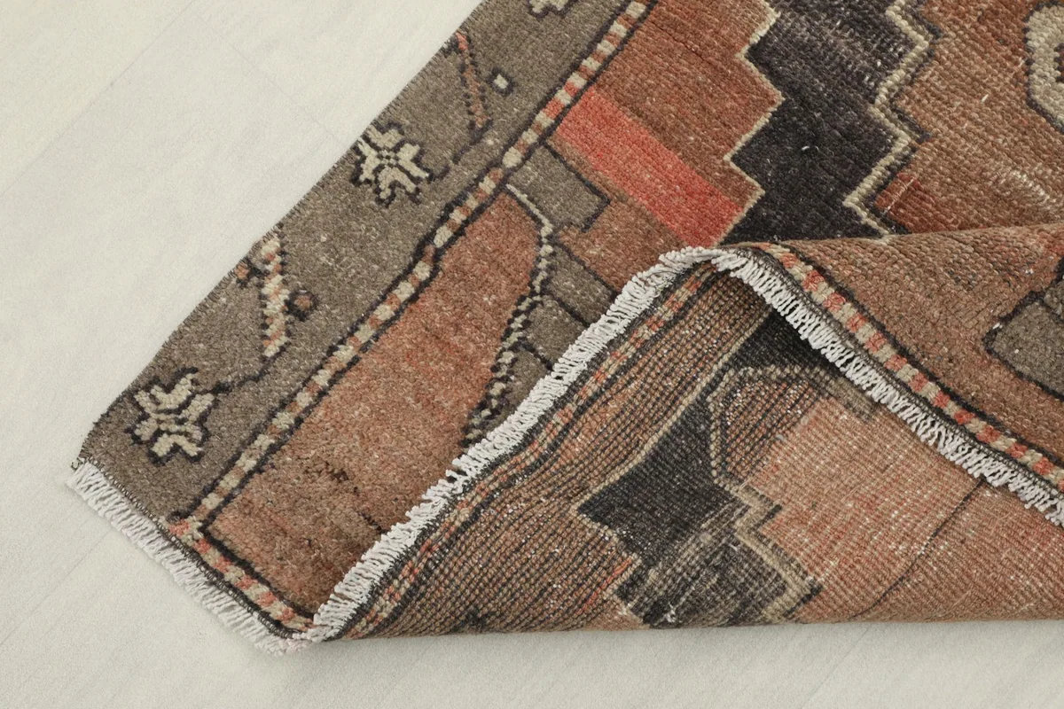 Corner view of the rug, showing the short fringe and the reverse side of the corner.
