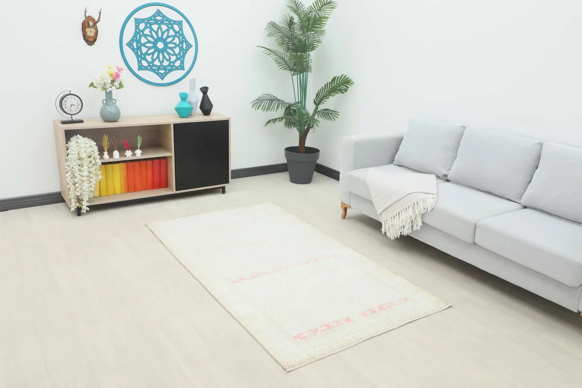 Cream and rose vintage rug styled in a modern living room setting with a gray sofa and light wood floor.