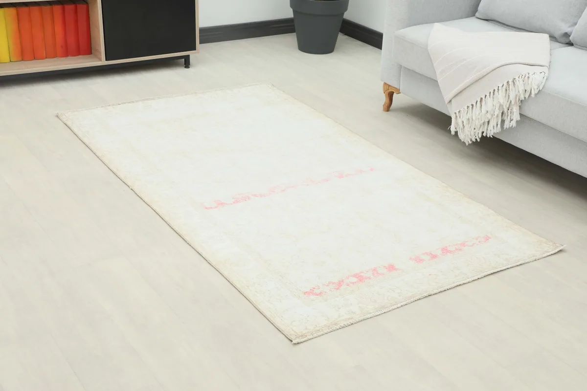 Angle view of the cream and rose vintage rug in a living space, showing its size relative to furniture.
