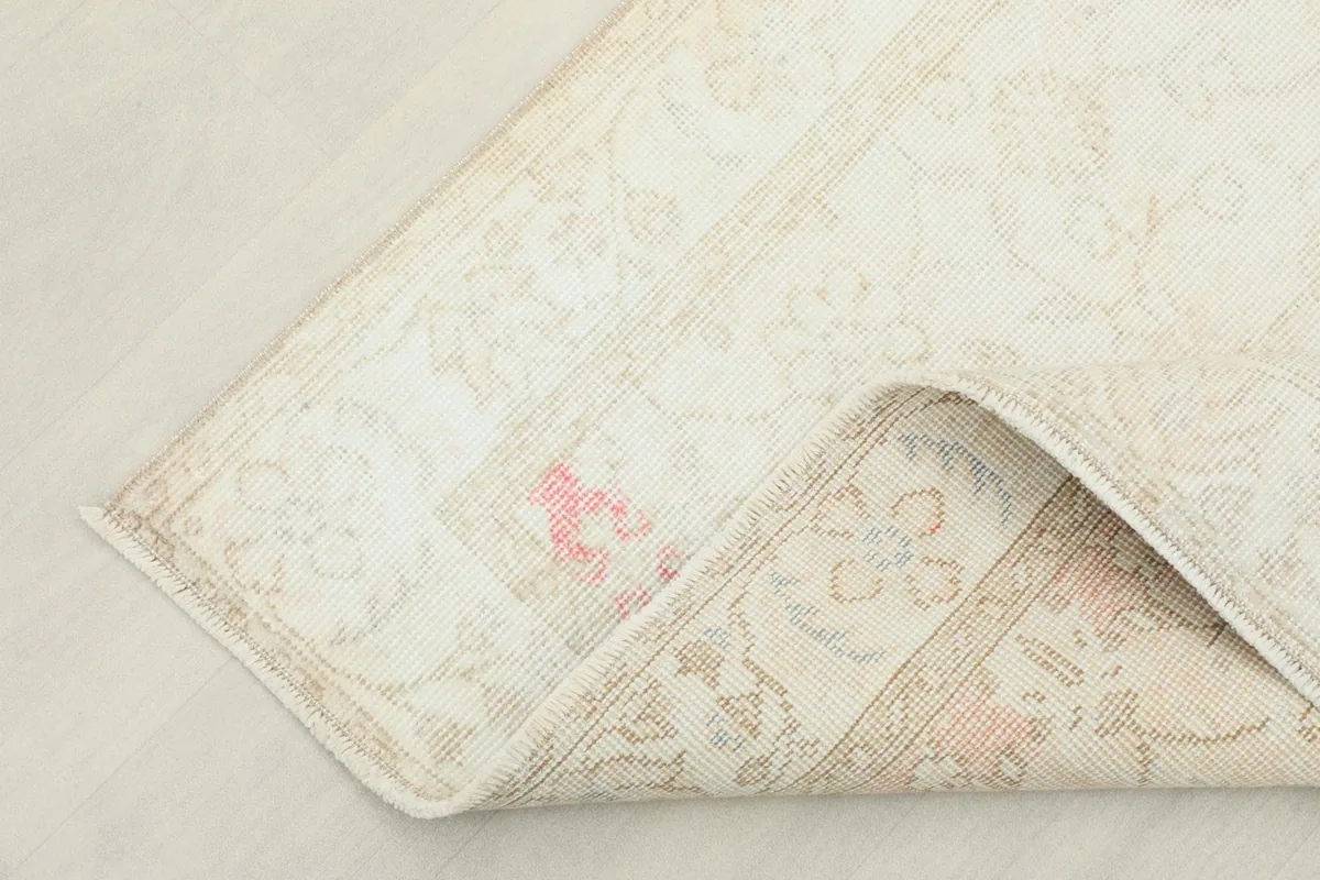 Corner of the rug folded back, revealing the reverse side of the hand-knotted wool and cotton foundation.