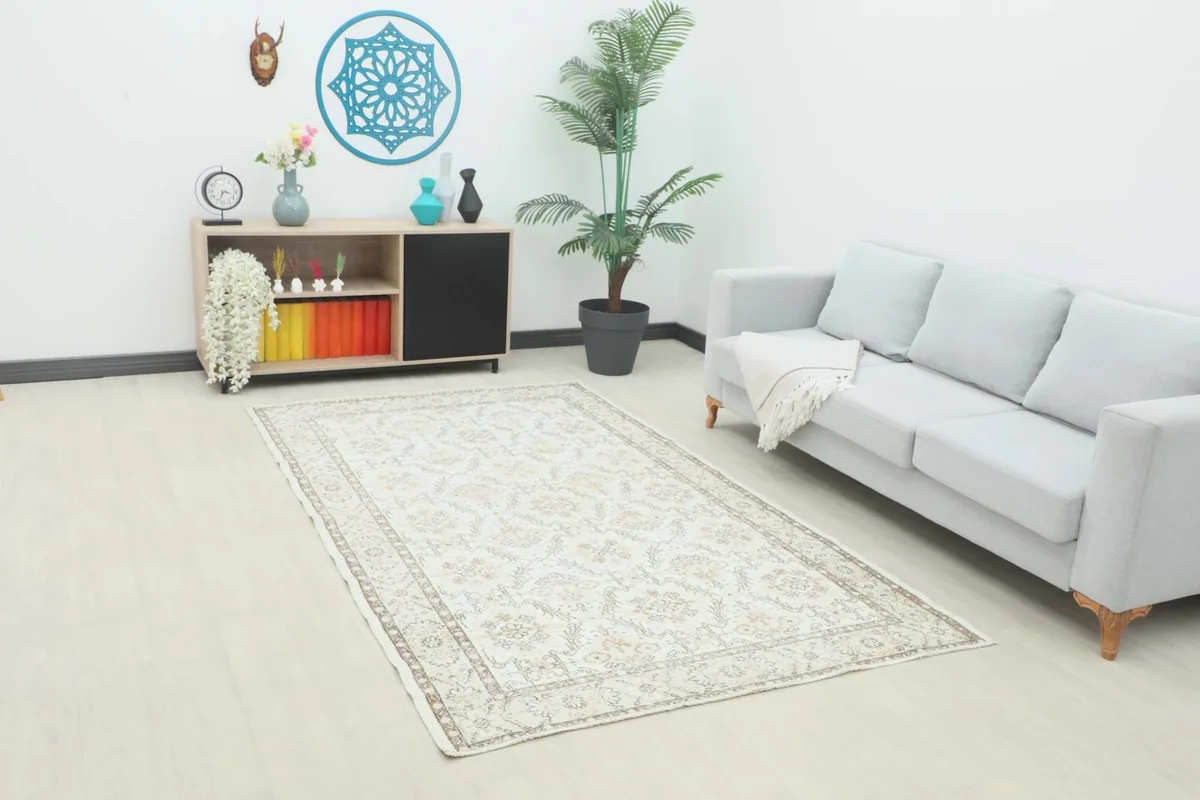 Ivory beige floral rug placed in a modern living room setting with a gray sofa