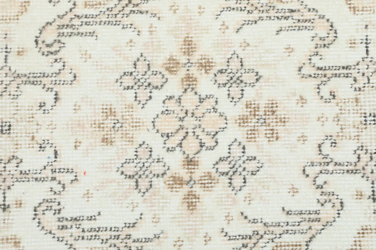 Close-up of a specific floral motif in beige and gray on the ivory background