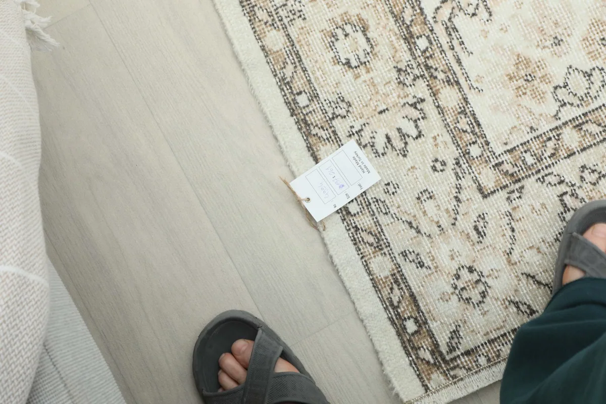 Overhead view of a section of the rug, including a tag and feet for scale