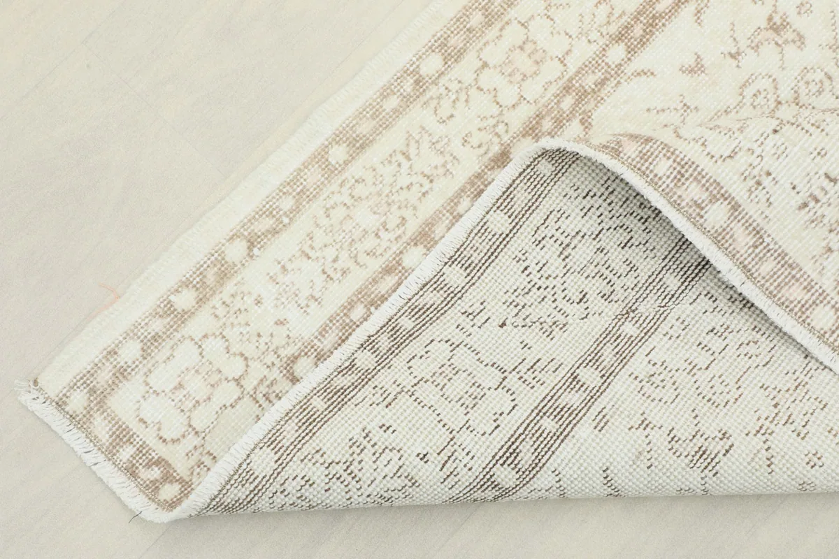 View of the rug's underside and folded corner, showing the hand-knotted cotton foundation