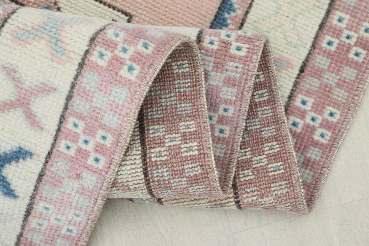 Close-up of the rug's edge and fold, showing the tightly woven cotton foundation and wool pile