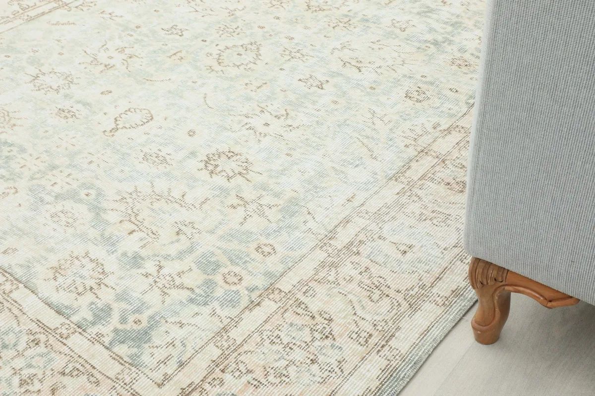 Close-up of the rug next to a sofa leg, illustrating its scale and how it complements home decor.