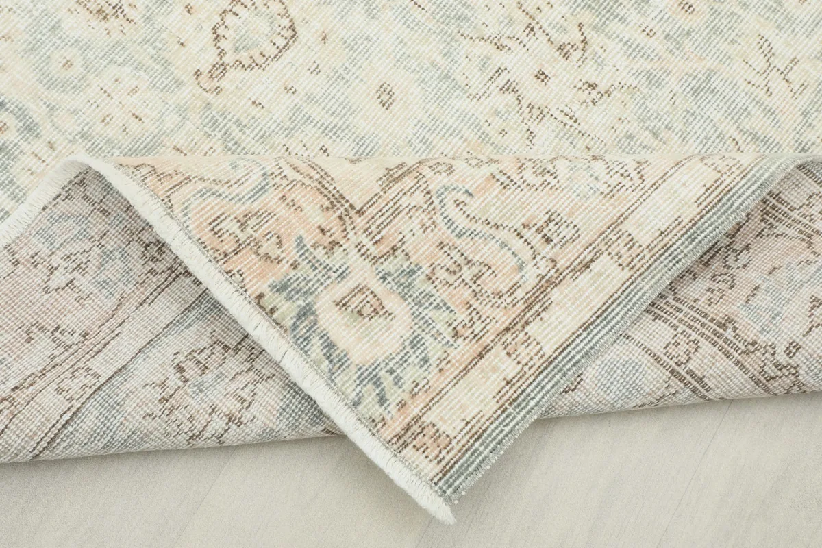 Corner of the rug folded back, showcasing the reverse side of the hand-knotted cotton foundation.