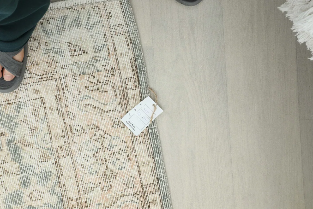 Overhead view of the rug with a small tag, showing its natural patina and subtle color variations.