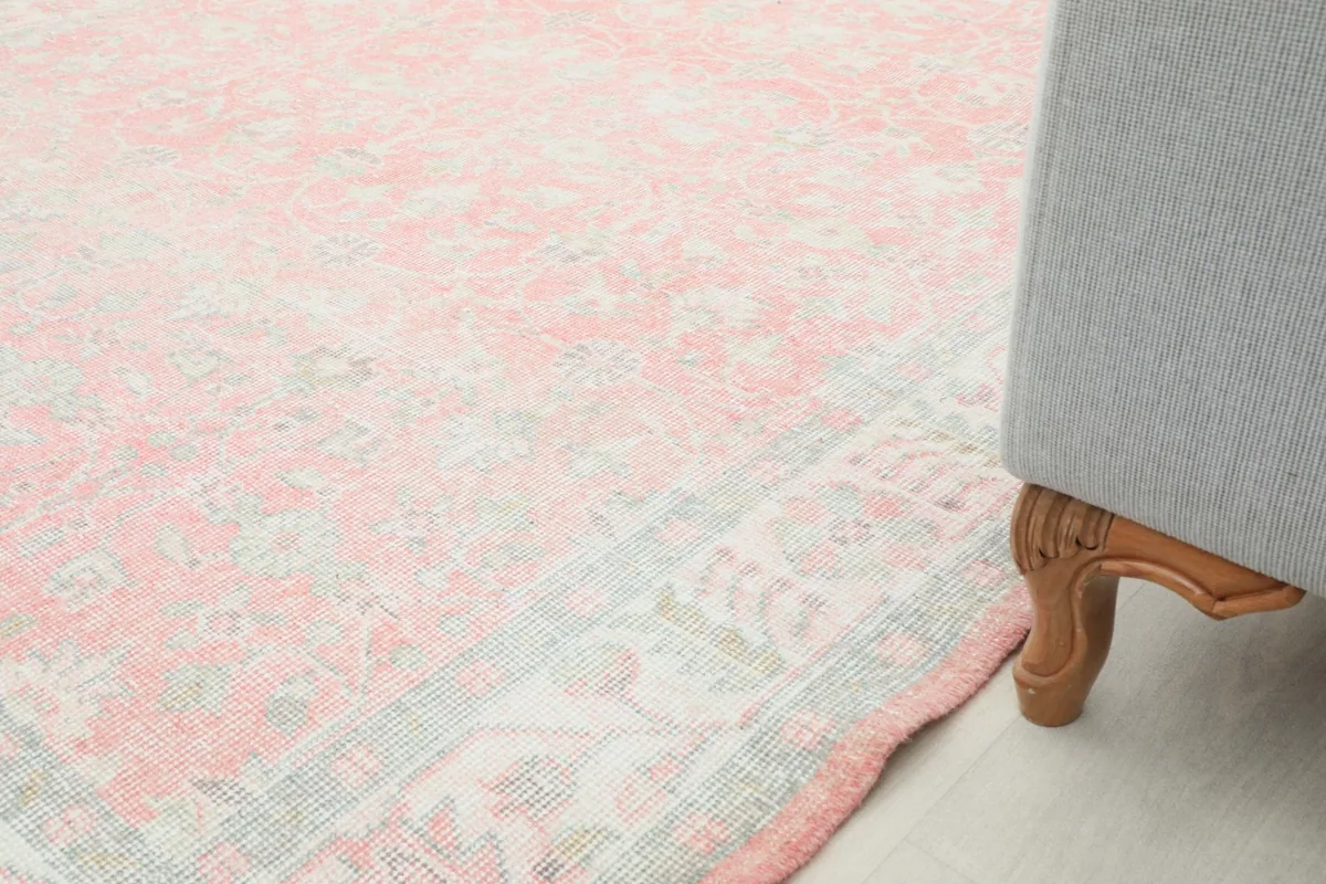 Partial view of the rug on a light floor, with a sofa leg in the foreground