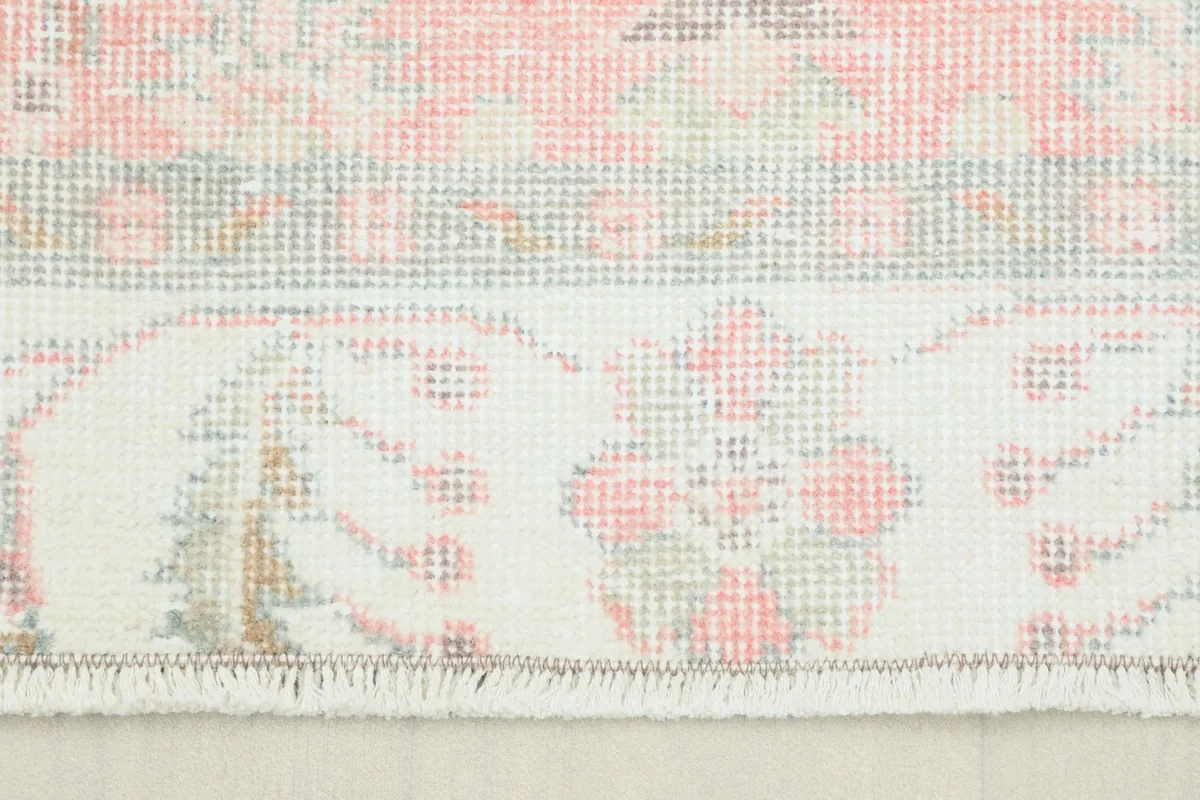 Close-up view of the rug's short fringe and the ivory border with floral motifs