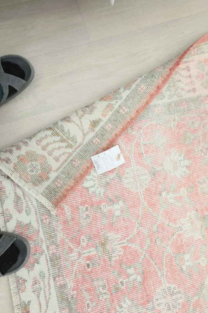 View of the rug's underside and a label, with sandals nearby for scale