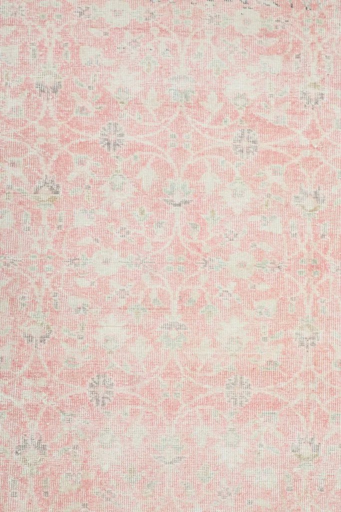 Overhead view showing the faded pink field and subtle floral patterns of the rug