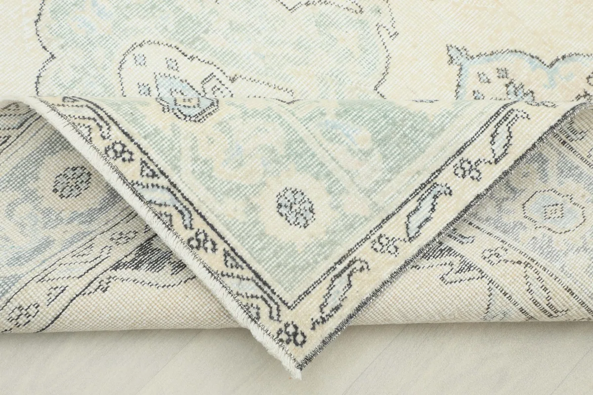 Corner of the rug folded back to reveal the cotton foundation and hand-knotted construction.