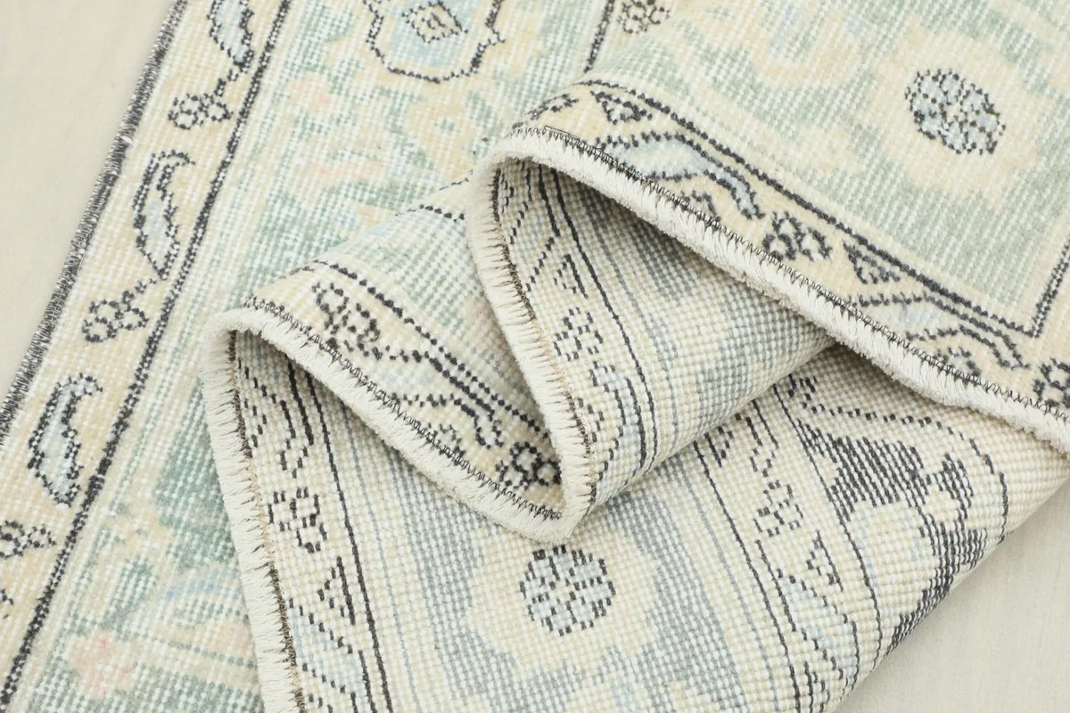 View of the rug folded, showing the flexibility and texture of the vintage wool material.