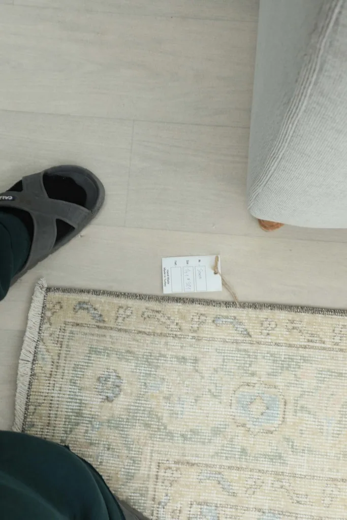 Overhead view of the rug's end, showing its fringe and a person's foot for scale.