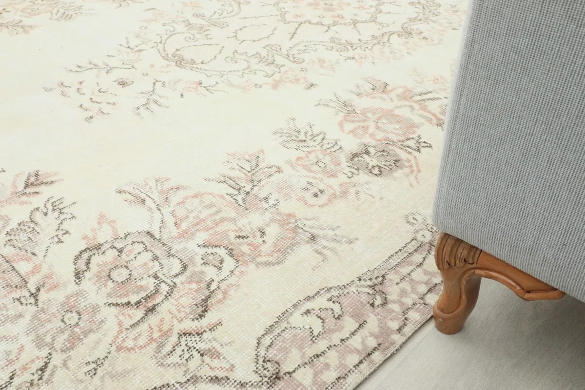 Detail view of the rug's floral border next to a sofa leg, showing the scale and pattern