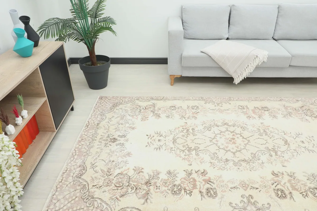 Angle view of the ivory and rose rug in a living space, showing its placement in front of a sofa