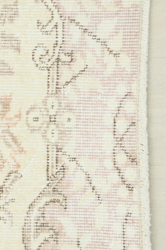 Close-up view of the rug's edge, showing the subtle rose and gray patterns and fringe detail