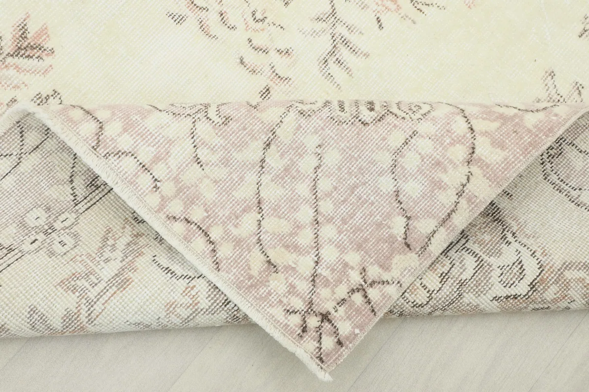 Folded corner of the rug revealing the hand-knotted construction and cotton foundation from the reverse side