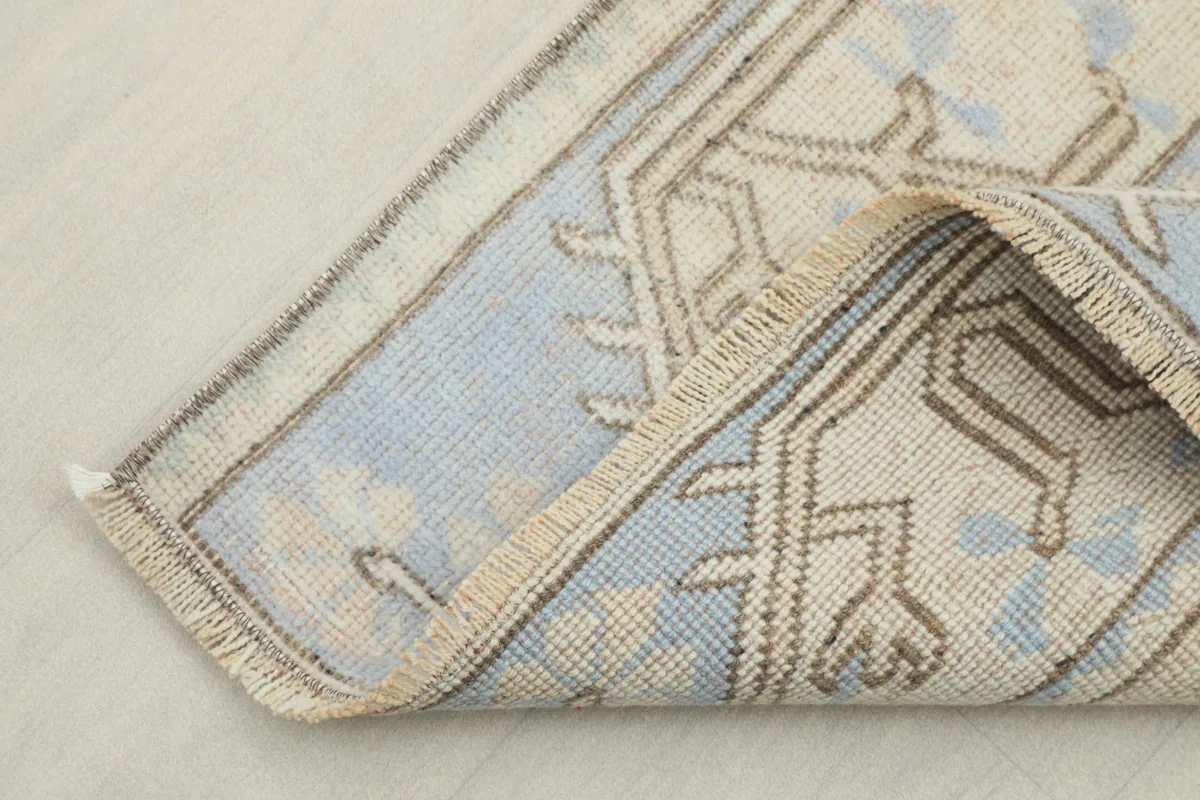 Corner of the runner folded back, showing the cotton foundation and reverse side of the knotting