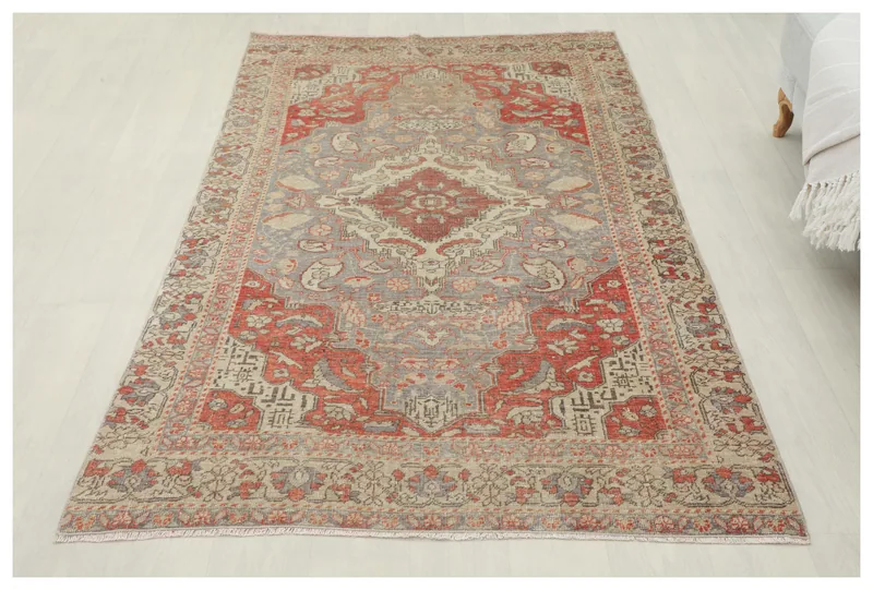 Full overhead view of the vintage Anatolian rug with a red and gray medallion on a beige field.