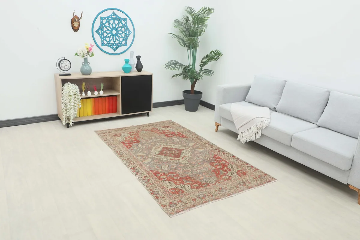 The red and gray vintage rug placed in a modern living room setting, showing its scale.