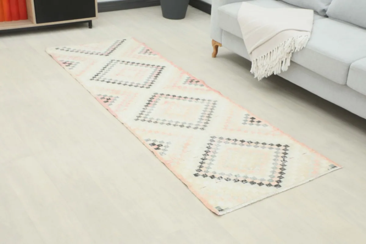 Angled view of the runner in a room, highlighting the ivory, rose, gray, and black geometric pattern.