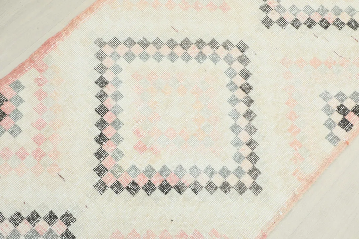 Detailed view of a central diamond motif, showcasing the intricate weave of small squares in ivory, rose, gray, and black.
